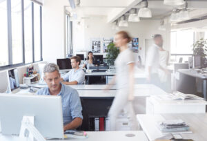 Busy open-concept office with employees working on computers.