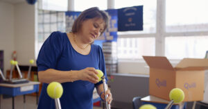 Teacher installing tennis balls to chair legs