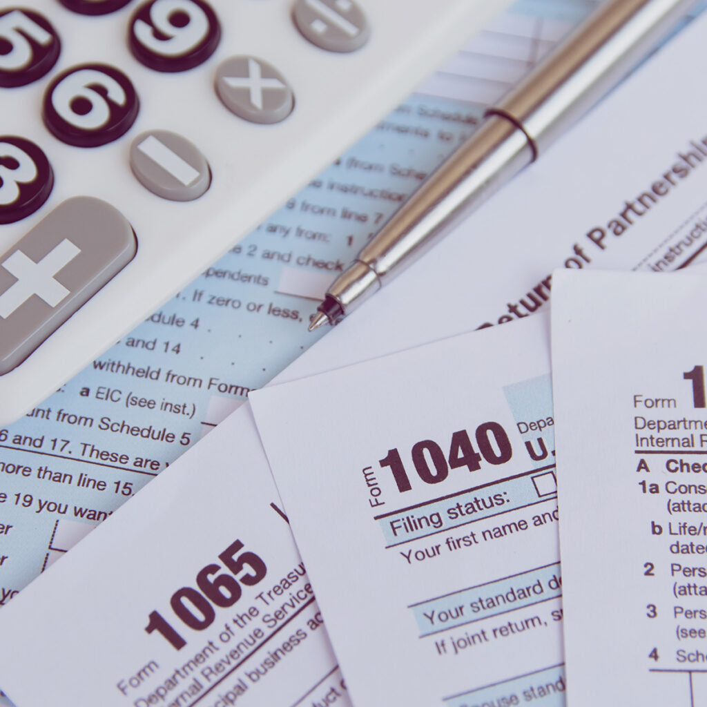 1040 and 1064 tax forms next to a calculator.