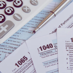 1040 and 1064 tax forms next to a calculator.