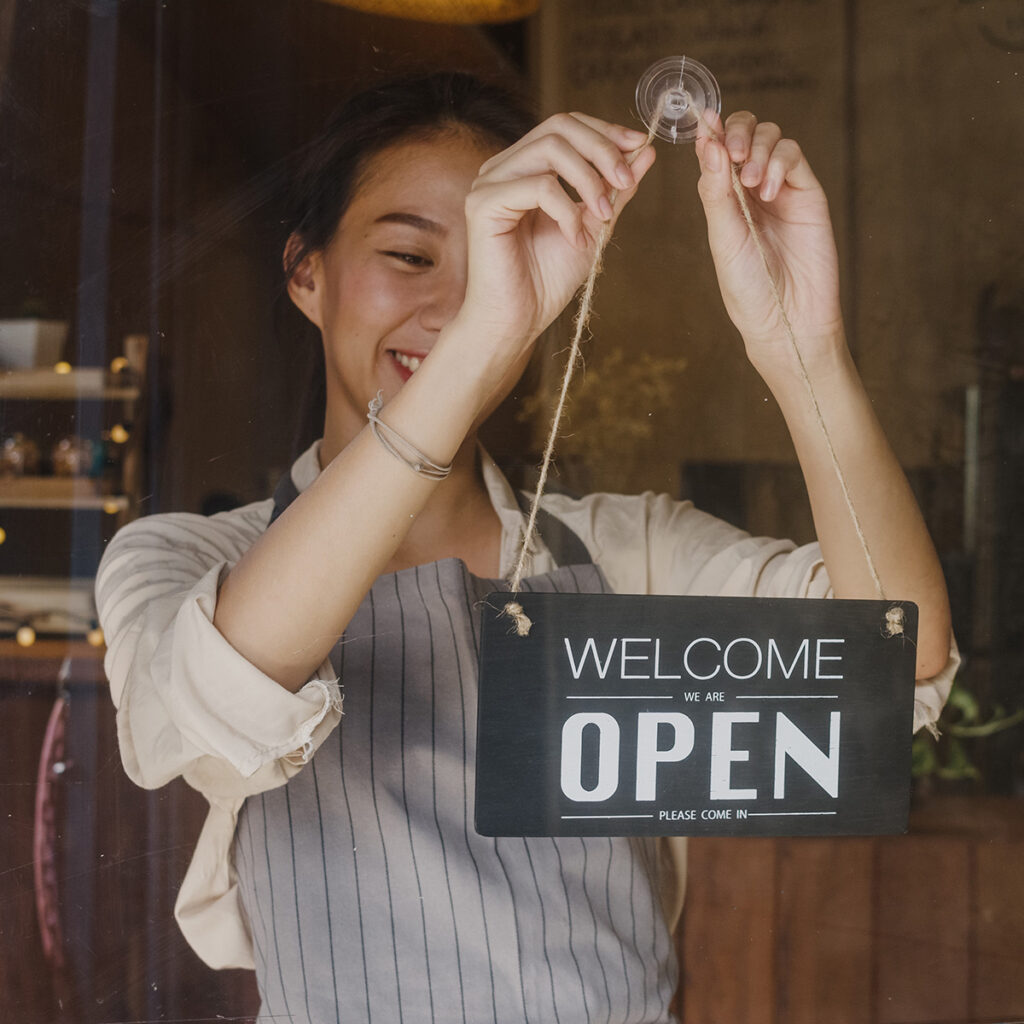 a lady pulling up "open" sign on the door