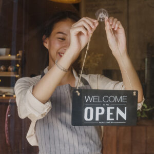 a lady pulling up "open" sign on the door