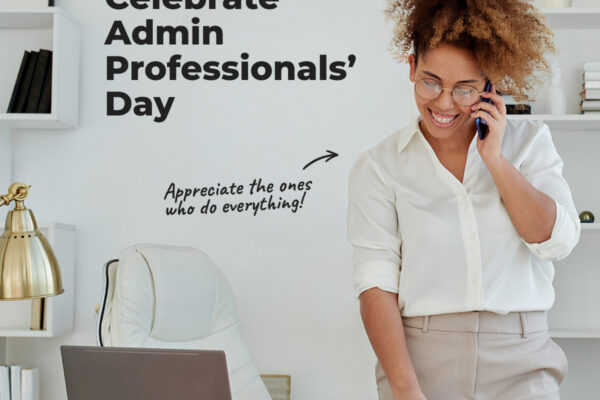 A woman standing in front of a desk talking on phone