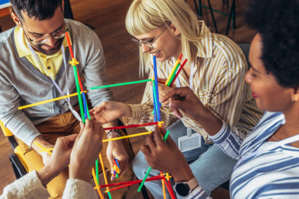3 people playing building sticks together