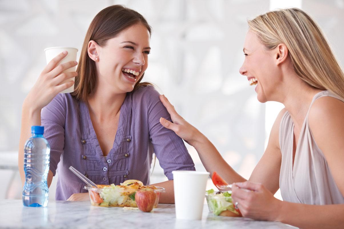 Two women laughing and eating lunch
