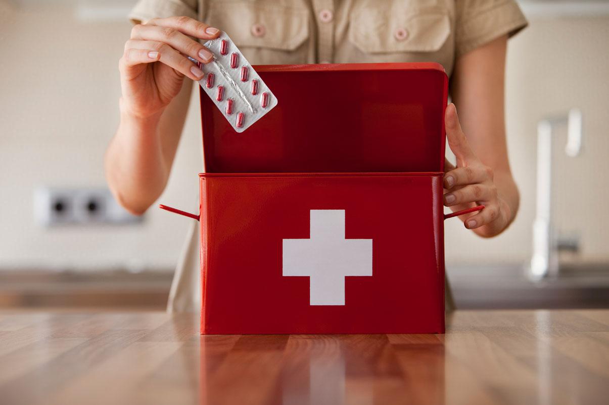 Woman pulling medicine from a first aid kit