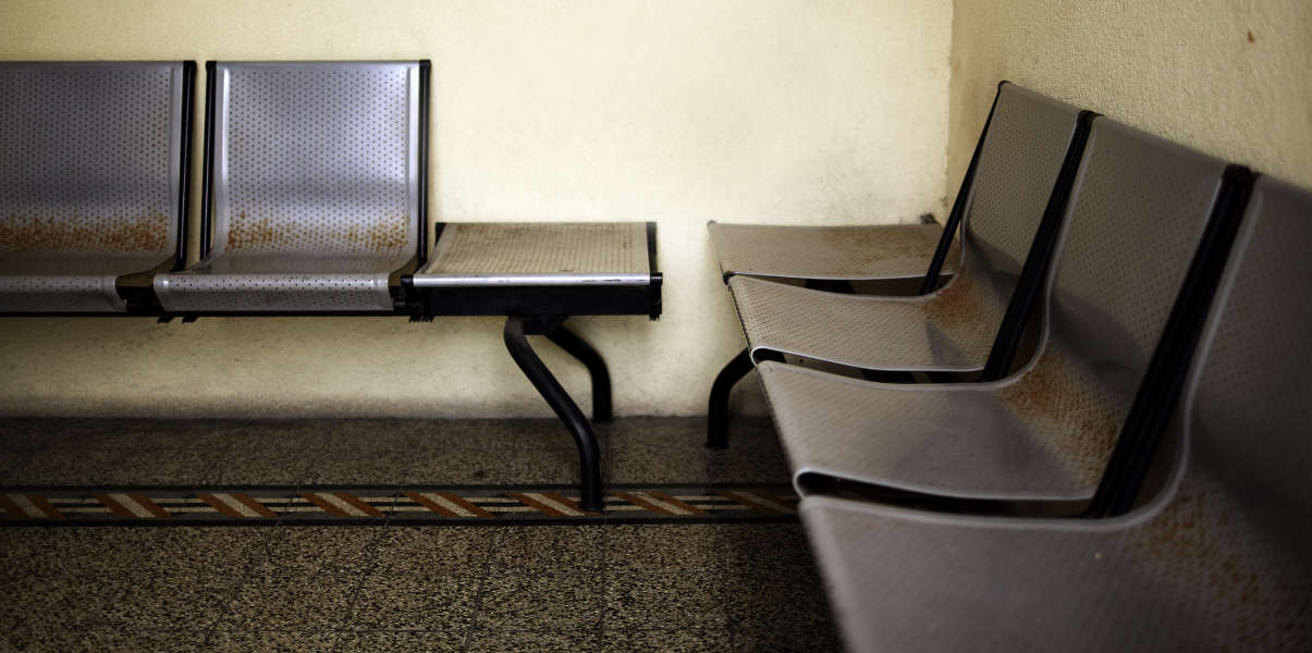 Rusty metal seating in a bare waiting room.