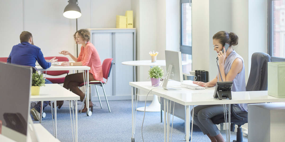 Woman using an L-shaped desk in a bright office environment