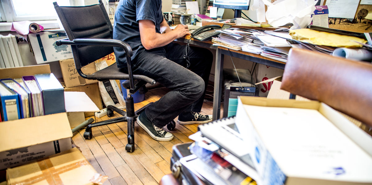 Man working in a messy, cluttered office.