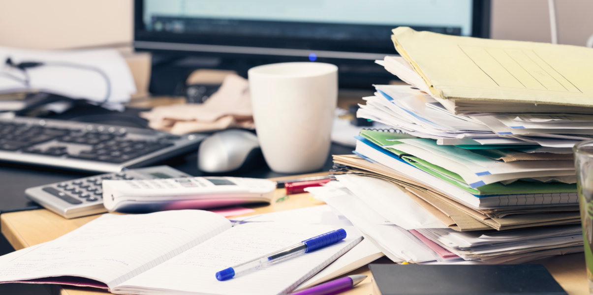 Close-up of messy desk covered in loose papers.