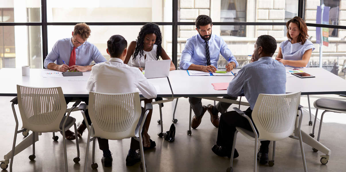 Coworkers collaborating around two pushed-together meeting tables.