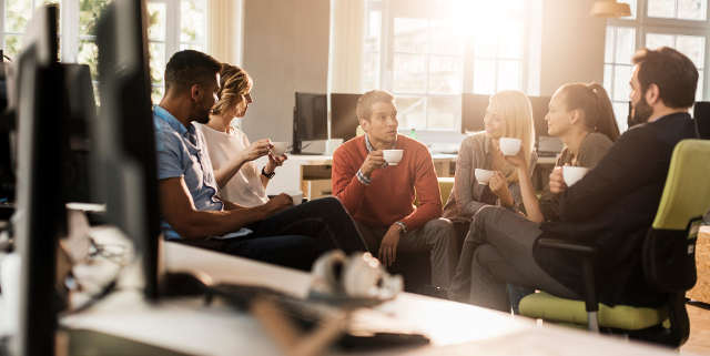 Coworkers having coffee break in bright office