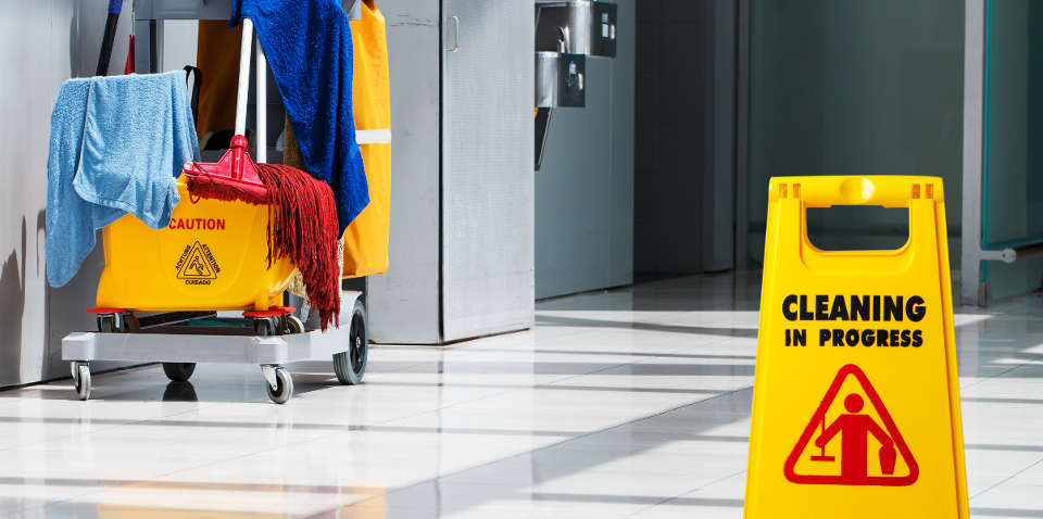 Janitor cart with mop, bucket and safety sign.