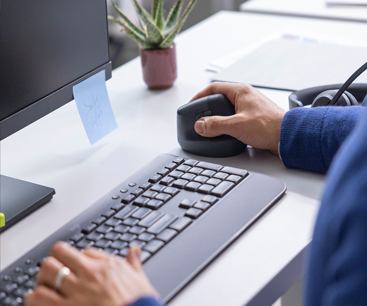 image of a person holding a mouse and typing on a keyboard on the desk